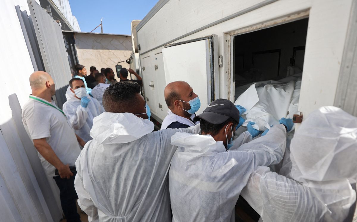 Trabajadores de la morgue descargan los cuerpos de palestinos. (AFP)