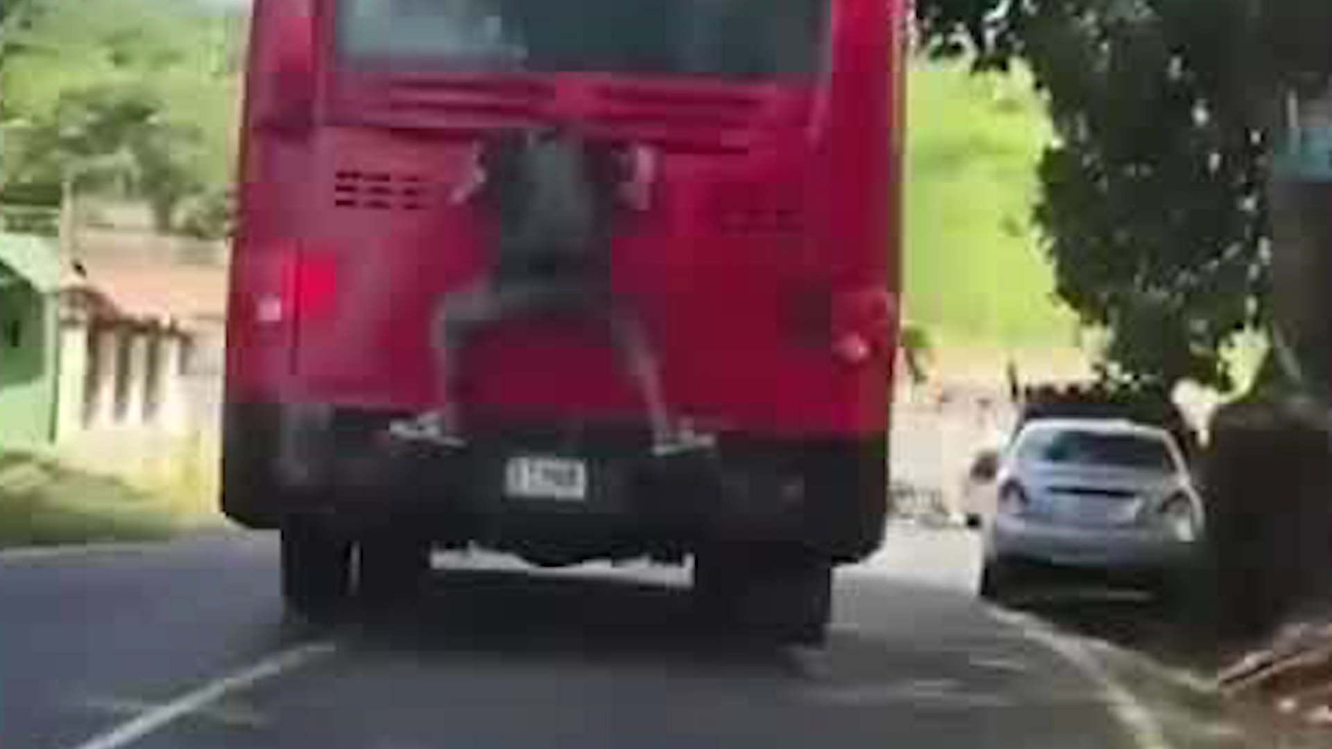 Hombre viaja colgado en parte trasera de un bus